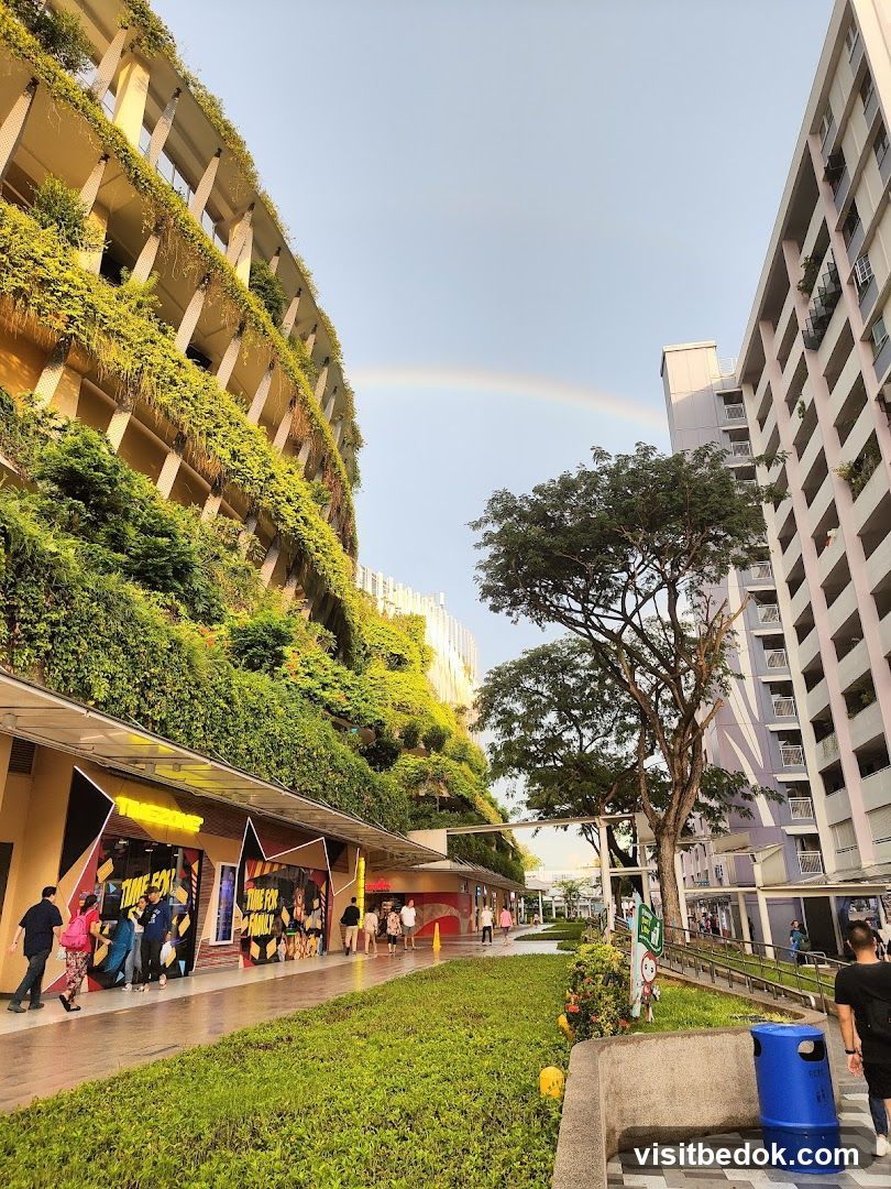 Outdoor walkway with shops and a rainbow