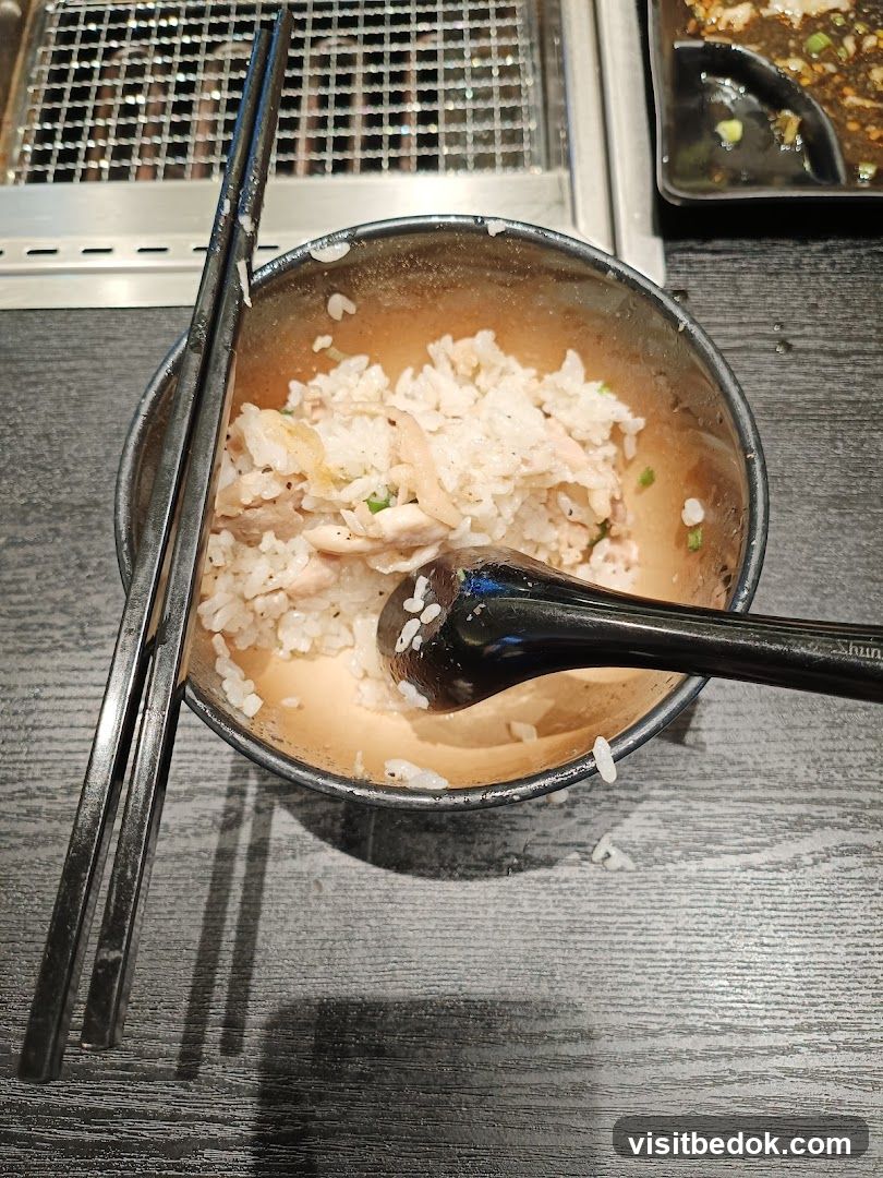 Bowl of rice with chicken and chopsticks