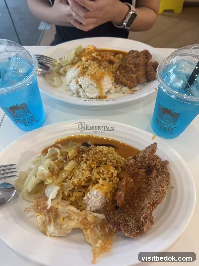 Two plates of rice with fried chicken and drinks