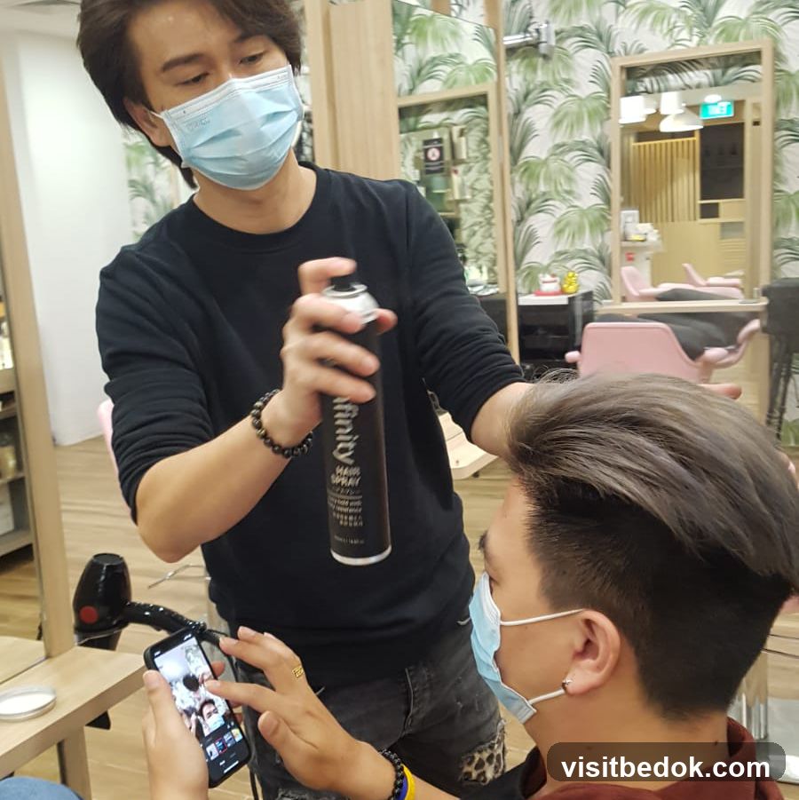 Hairdresser spraying hairspray on client