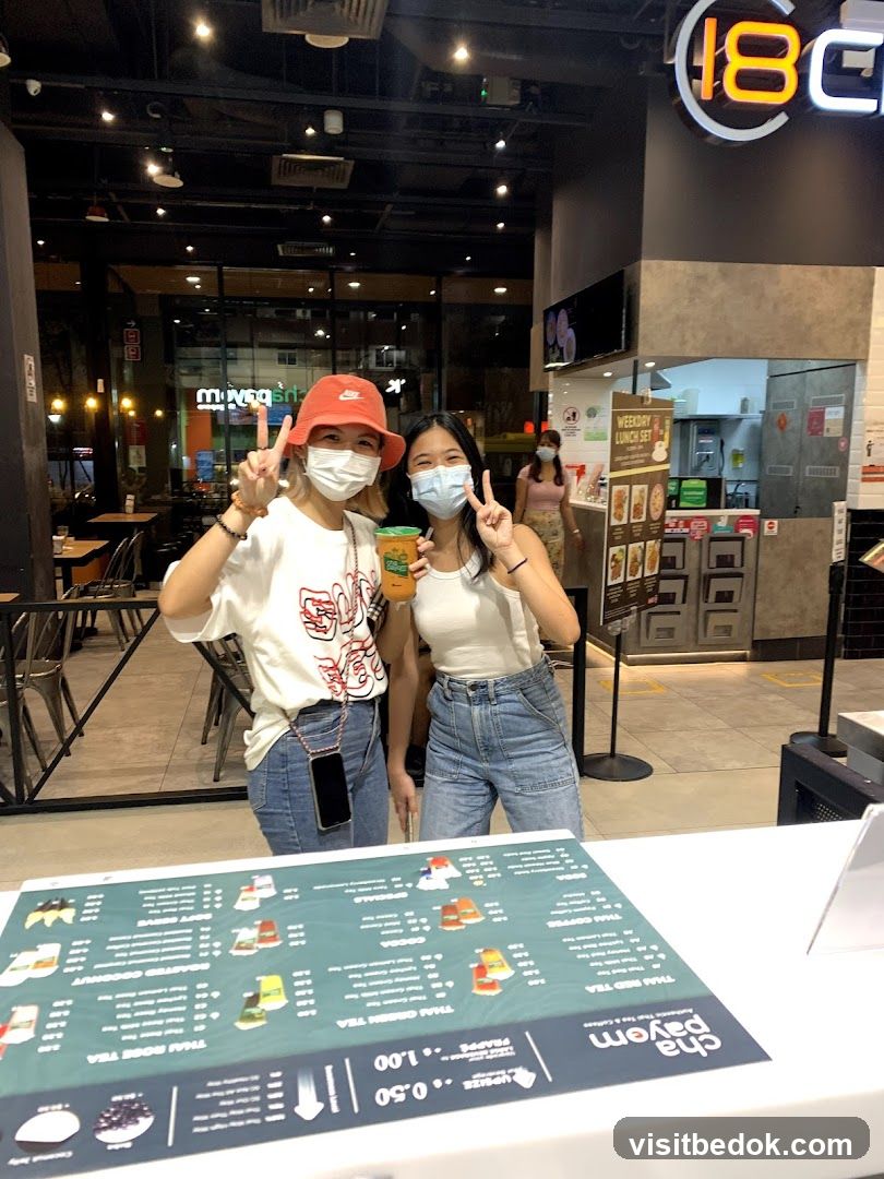 Two women posing with drinks in front of a food establishment