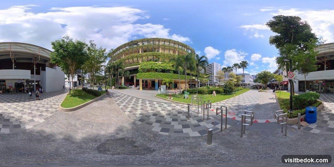Outdoor plaza with a multi-level building covered in greenery
