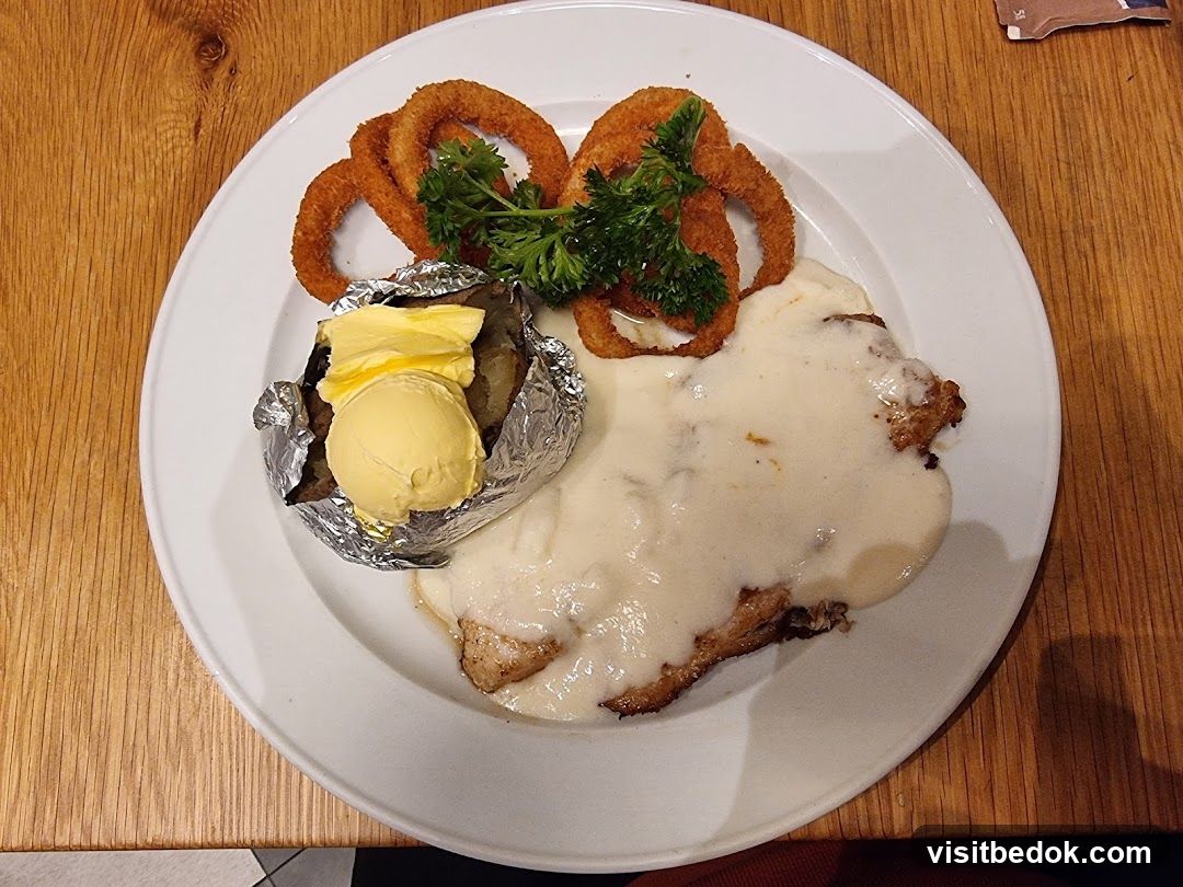 Chicken dish with baked potato and onion rings