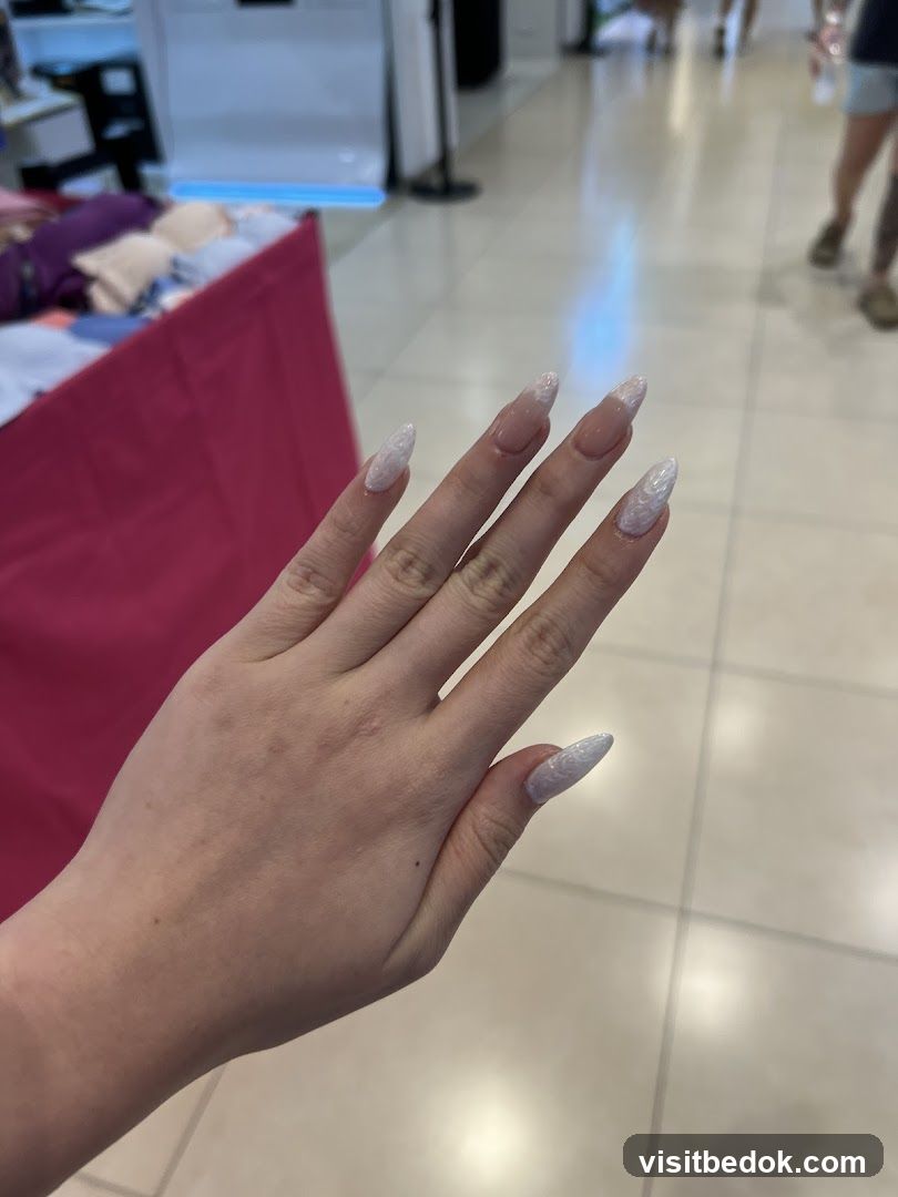 Hand with long, white, patterned nails