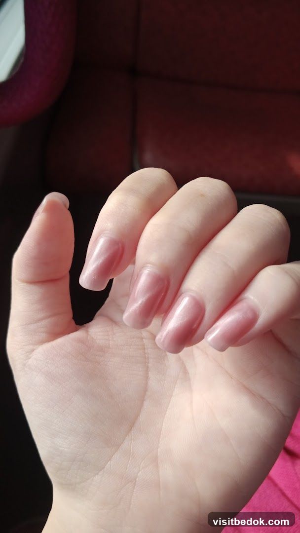 Close-up of a hand with light pink, square-shaped nails