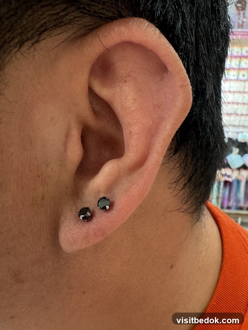 Close-up of a person's ear with two black stud earrings