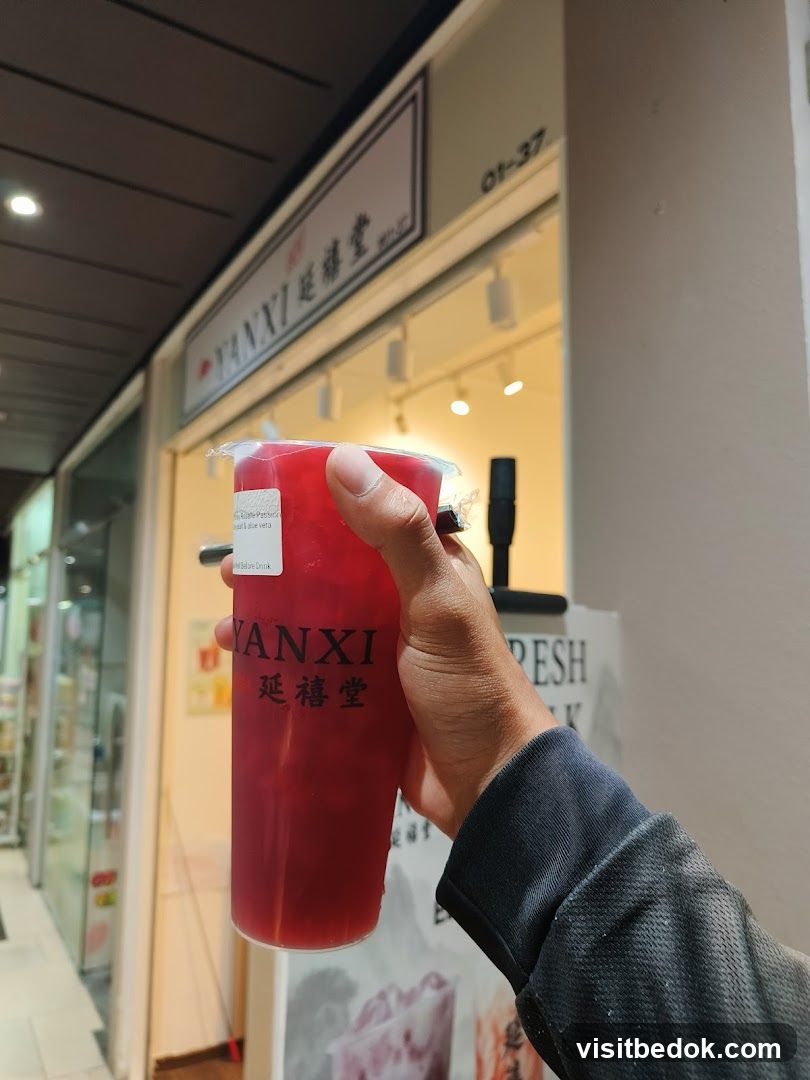 Person holding a drink in front of a shop