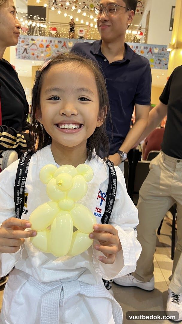 Girl in Taekwondo uniform holding a balloon animal