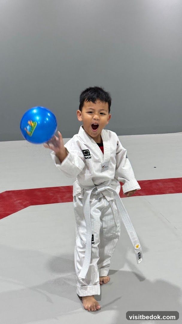 Young boy in Taekwondo uniform playing with a ball