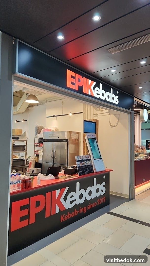 The exterior of a food stall with the name EPIK Kebabs prominently displayed. The stall features a counter with drinks and a digital ordering screen. The signage above the stall reads "EPIK Kebabs" in large, illuminated letters. Below the counter, the words "EPIK Kebabs Kebab-ing since 2012" are visible.
